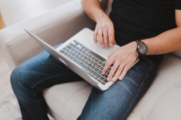 Mann mit Armbanduhr arbeitet am Laptop.